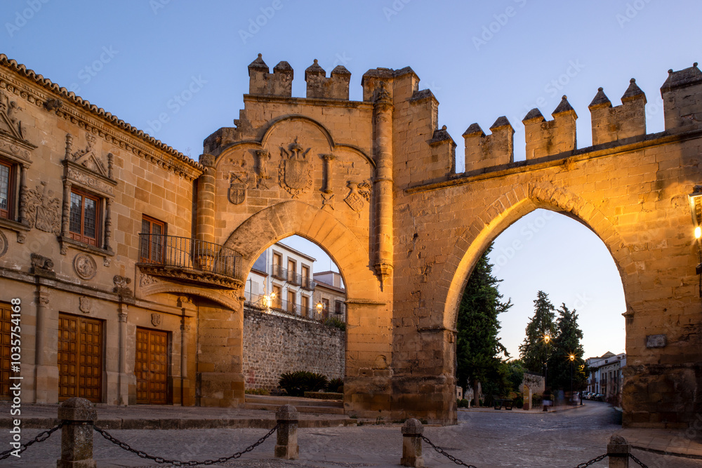 Fototapeta premium View of the Plaza de los Leones with the Jaén Gate and Villalar Arches in the background in Baeza, Jaén, Andalusia, Spain at dusk