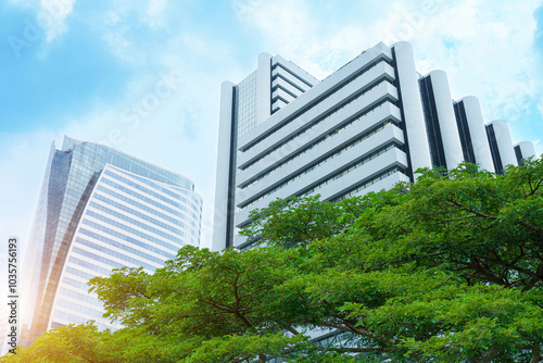 Eco-friendly building in the city. Sustainable glass office building with big tree for reducing heat and carbon dioxide. Office building with green environment. Corporate building reduce CO2.