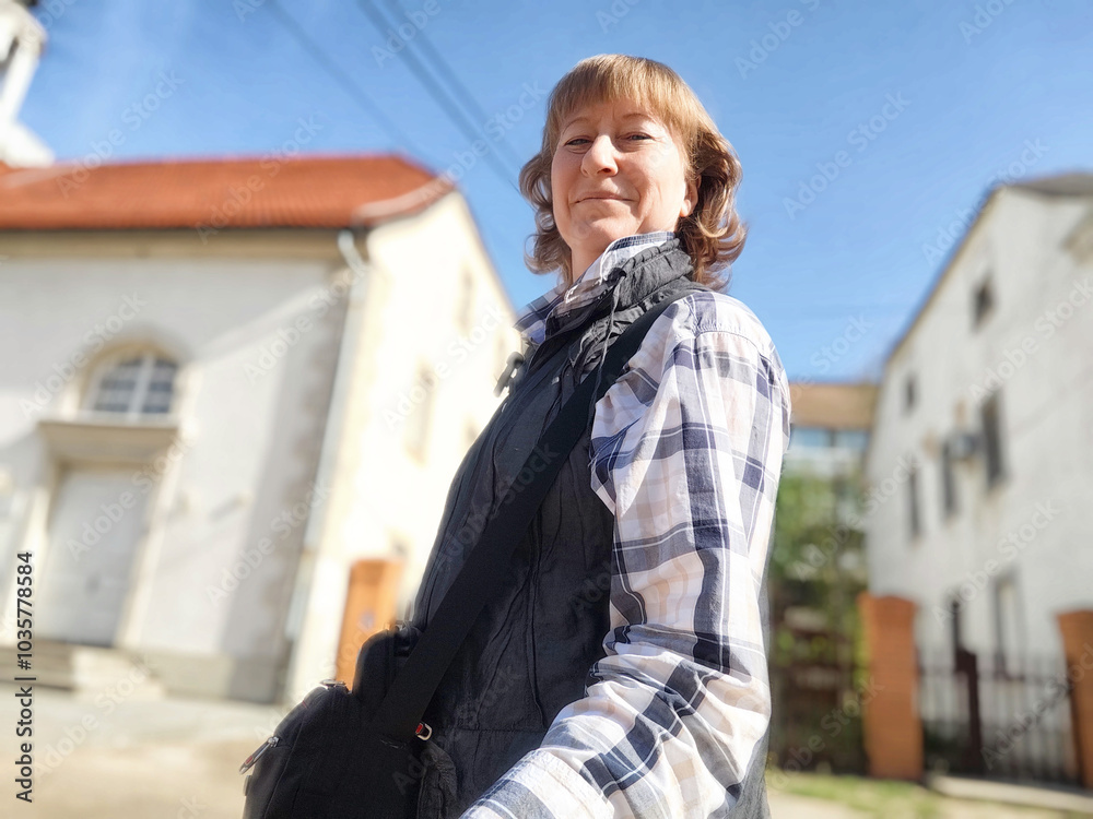 The woman enjoys her travels while taking in the charming architecture of the European town. The adventures of a middle-aged female tourist on a trip The woman enjoys her travels while taking in the charming architecture of the European town. The adventures of a middle-aged female tourist on a trip