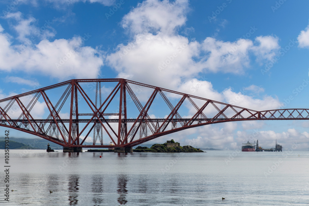 Ship sailing under the red Forth cantilever railway bridge across the Firth of Forth, Queensferry, UK near Edinburgh Ship sailing under the red Forth cantilever railway bridge across the Firth of Forth, Queensferry, UK near Edinburgh