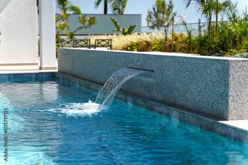 Swimming pool at sunny day with waterfall closeup