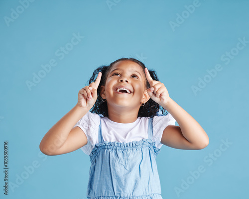 Studio, child and pointing with smile for marketing, product placement and branding by mockup space. Kid, girl and showing with gesture for advertising, sale or back to school deal by blue background