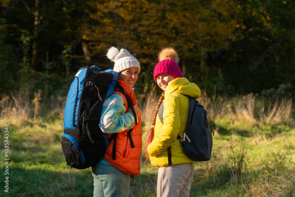 family walking in autumn forest with backpacks, boy in yellow jacket, girl in pink jacket, mother in orange sleeveless jacket, family in hat with pompoms, gen z family walking in autumn forest with backpacks, boy in yellow jacket, girl in pink jacket, mother in orange sleeveless jacket, family in hat with pompoms, gen z