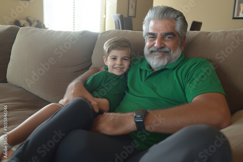 A joyful grandfather and grandson share a cozy moment on the couch at home