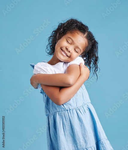 Self love, happy and child with hug in studio for sweet, embrace and development by blue background. Innocent, smile and little girl kid with gesture of care for affirmation, comfort and kindness