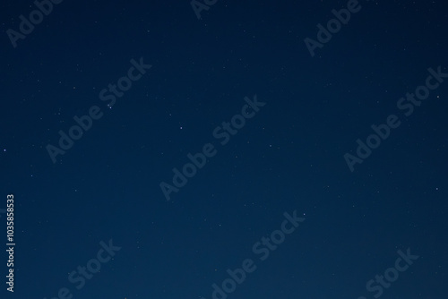 A peaceful night scene with a clear, star-filled sky above silhouettes of autumn trees. The serene atmosphere highlights the beauty of the dark sky and stars.