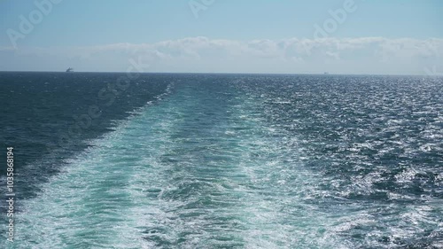 Ferry Creates Rippling Waves on Tranquil Sea Under Clear Sky, Illustrating Passage of Time and Travel on Ocean. Sea waves background get away ship side, cruise vacation and relaxation on open ocean