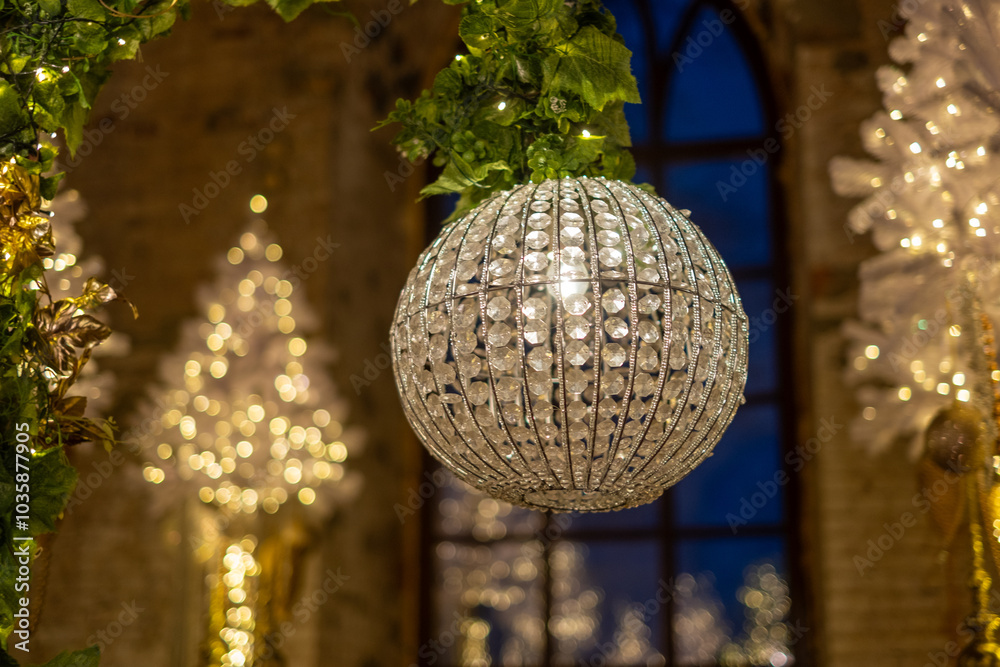 Obraz premium Elegant crystal chandelier hanging in a beautifully decorated hall during festive celebrations at night.Background with Luxurious Christmas decorations and crystal chandeliers and lights