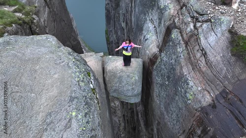 Girl Adventurist is Jumping on Kjeragbolten in Norway. Kjerag Boulder in Mountains Fjord Landscape Aerial view.