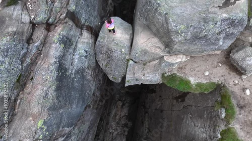 Girl Adventurist is Jumping on Kjeragbolten in Norway. Kjerag Boulder in Mountains Fjord Landscape Aerial view.
