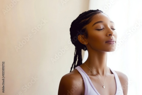 Serene young woman meditating with calm expression and braided hair