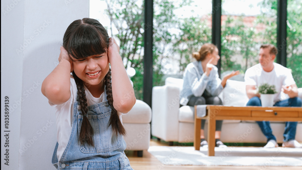 Stressed and unhappy young girl huddle in corner, cover her ears blocking sound of her parent arguing in background. Domestic violence at home and traumatic childhood develop to depression. Synchronos Stressed and unhappy young girl huddle in corner, cover her ears blocking sound of her parent arguing in background. Domestic violence at home and traumatic childhood develop to depression. Synchronos