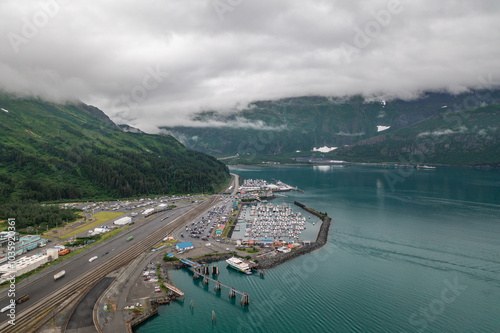 Aerial view of boat harbor, town shops and businesses and surrounding mountains of Whittier, Alaska city landscape 