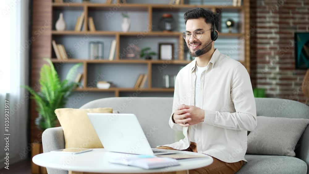 Confident businessman in wireless headset talking on a video call using laptop sitting in home office. Entrepreneur has online business meeting with partner. The teacher speaks remotely with students Confident businessman in wireless headset talking on a video call using laptop sitting in home office. Entrepreneur has online business meeting with partner. The teacher speaks remotely with students