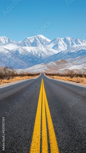 A straight road with a vivid yellow line extending towards snowy mountain peaks