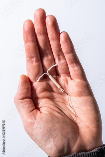 hand holding a hormonal IUD birth control contraception on a white background 