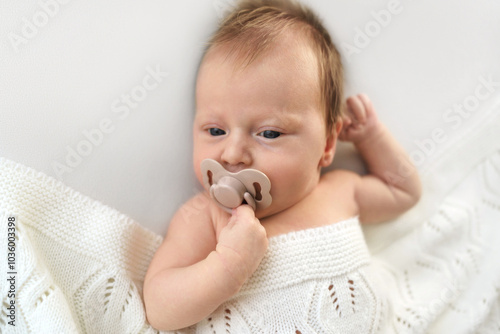 Adorable newborn relaxing with pacifier wrapped in soft blanket. High quality photo photo