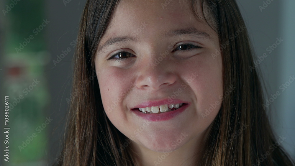 Close-up of a smiling young girl, looking directly into the camera with a natural expression, showing a warm and friendly demeanor in a home environment Close-up of a smiling young girl, looking directly into the camera with a natural expression, showing a warm and friendly demeanor in a home environment