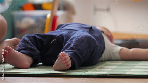 Close-up of a baby lying on a play mat, showing the baby’s legs and feet in a relaxed position during playtime in a cozy home environment