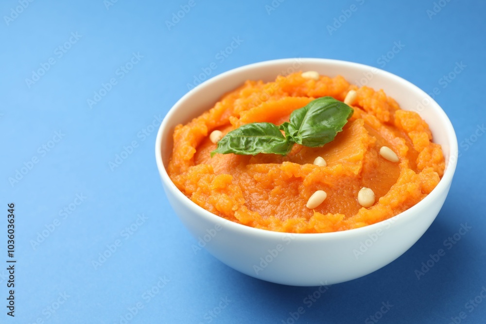 Tasty mashed sweet potato with basil and seeds in bowl on blue background, closeup Tasty mashed sweet potato with basil and seeds in bowl on blue background, closeup