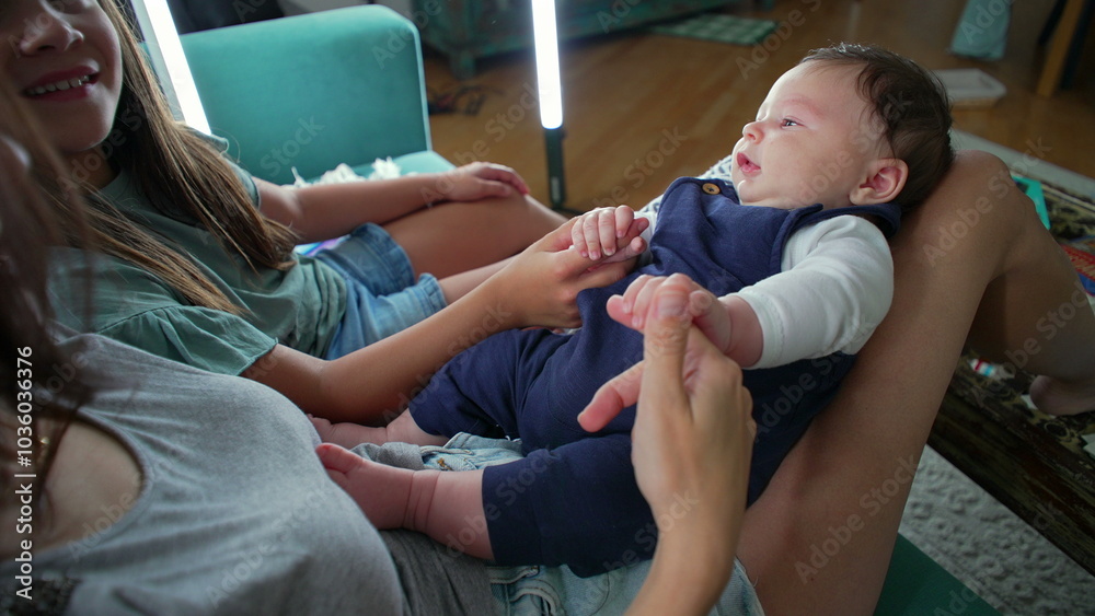 Mother and daughter holding and gently interacting with a baby in their lap, sharing an intimate moment of bonding and connection in a cozy home setting Mother and daughter holding and gently interacting with a baby in their lap, sharing an intimate moment of bonding and connection in a cozy home setting