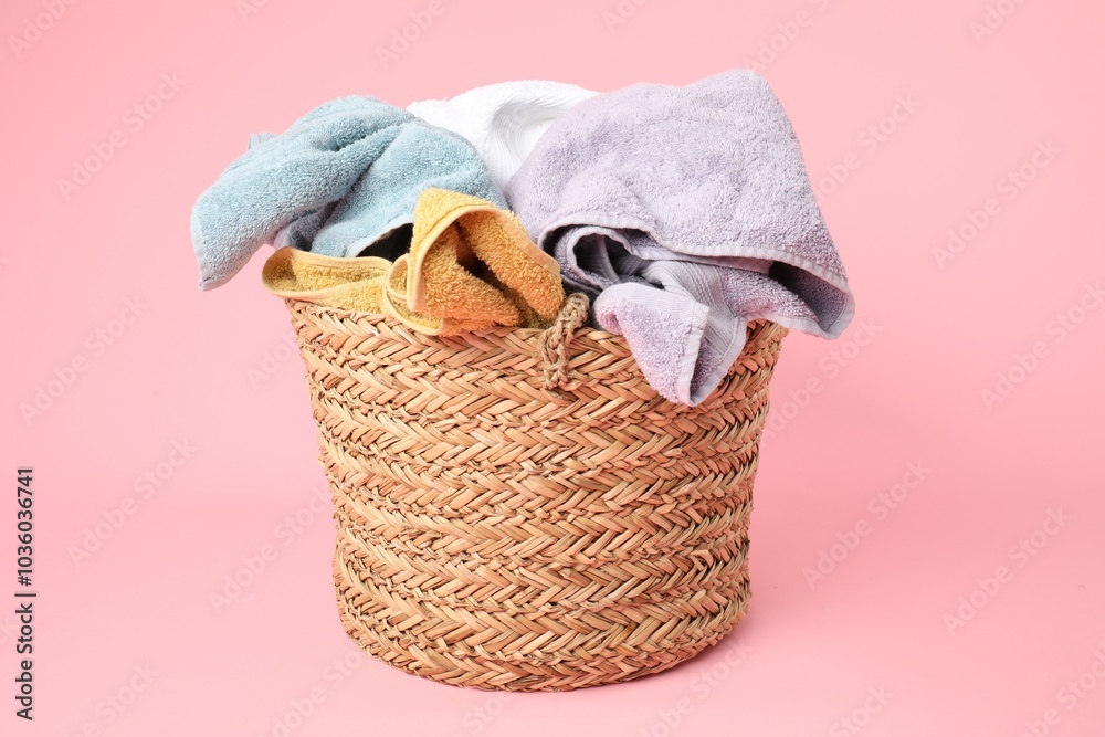 Obraz premium Wicker basket full of laundry on pink background
