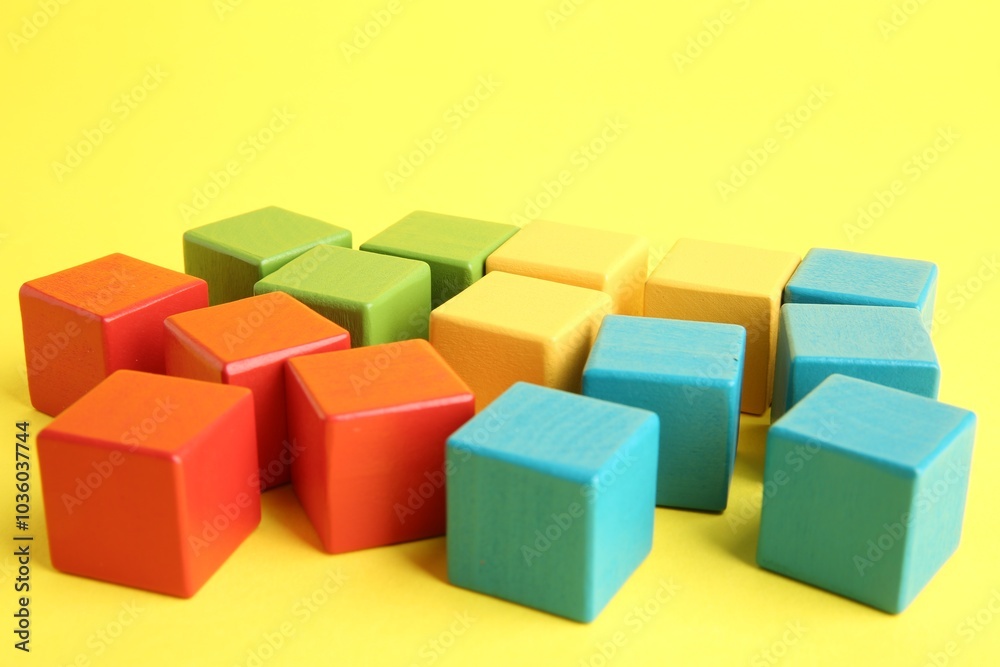 Many wooden colorful cubes on yellow background, closeup Many wooden colorful cubes on yellow background, closeup