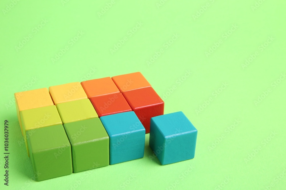 Many wooden colorful cubes on green background, space for text