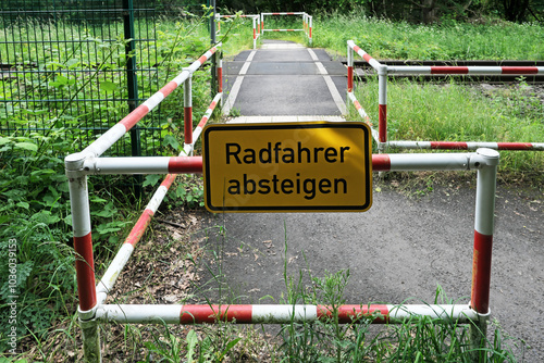 Umlaufgitter an Bahnübergang für Fußgänger mit Zusatzschild Radfahrer absteigen - Stockfoto photo