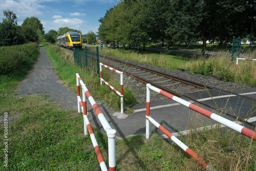 Bahnübergang für Fußgänger und Umlaufgitter und herannahender Zug - Stockfoto photo