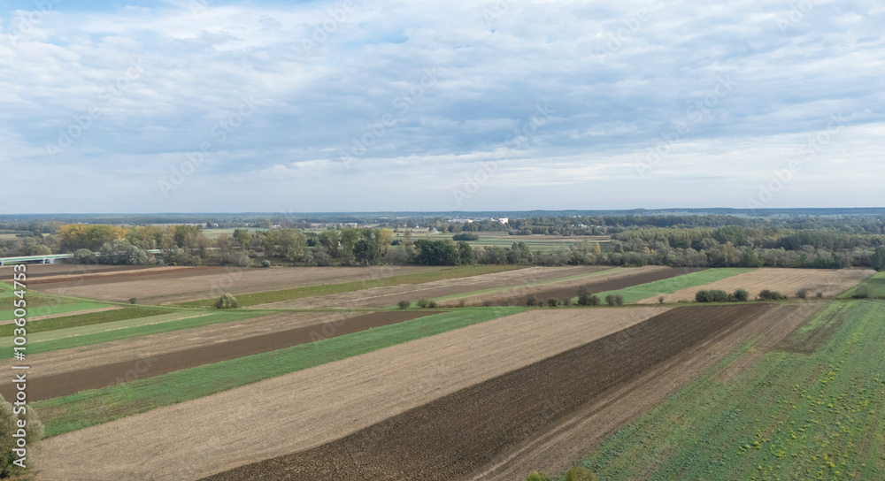 Aerial view of patchy agricultural fields with vibrant green and brown hues under a cloudy sky. Nature's beauty showcasing farmland and rural landscapes. Aerial view of patchy agricultural fields with vibrant green and brown hues under a cloudy sky. Nature's beauty showcasing farmland and rural landscapes.
