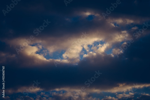 Dramatic sky with dark clouds revealing patches of blue and hints of light. photo