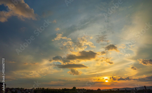 Stunning sunset with vibrant colors illuminating the sky and clouds over a distant landscape.