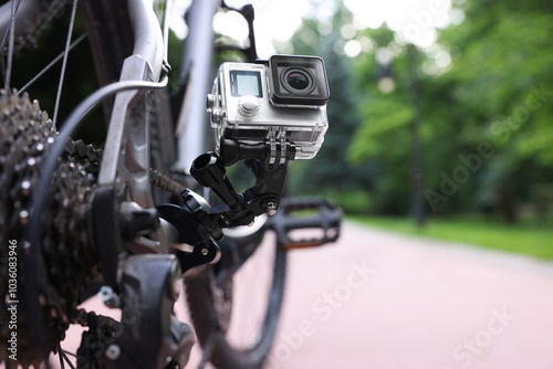 Modern action camera with mount on bicycle outdoors, closeup. Space for text