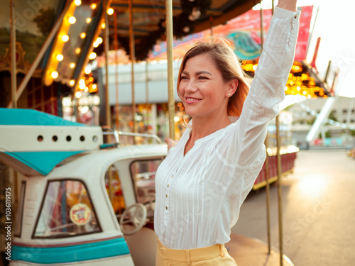 Close up portrait of a happy young woman on the carousel at the amusement park. Leisure and entertainment at funpark fair photo