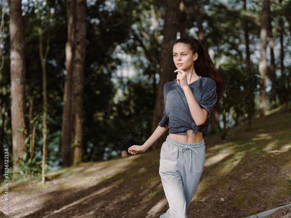 Young woman jogging in a forest, wearing athletic clothes and a determined expression, embodying health and fitness amidst nature Exercise and wellness concept Young woman jogging in a forest, wearing athletic clothes and a determined expression, embodying health and fitness amidst nature Exercise and wellness concept