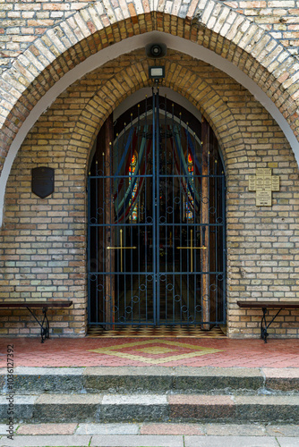 A large wooden church gate in a medieval church. The Gothic building is made of red brick. Decorative elements of the ancient temple.