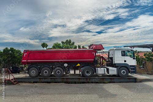 Truck with a dump semi-trailer for earthmoving mounted on an industrial weighing scale.