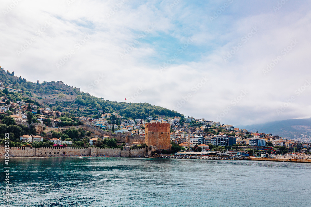 Fototapeta premium Landscape view old walls of fortress and Red tower on Mediterranean coast. View of Alanya Castle, stone ruins in harbor Alanya, Turkey. High quality photo
