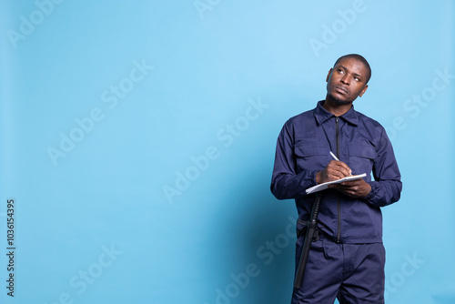 Fototapeta African american security agent writing details on his notebook files, keeps track of information while he is on safeguarding duty