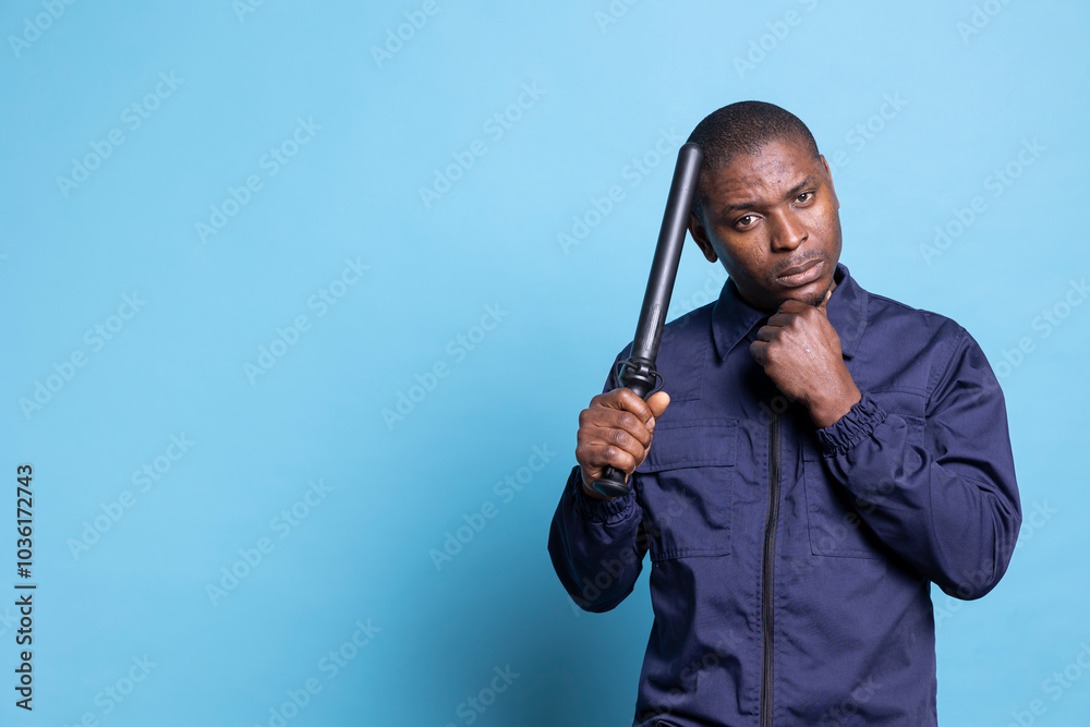 Dangerous skilled bodyguard posing with his baton weapon and clenched fist, making threats in case of fights or emergency defense. Agent on security and protection duty trained to punch. Dangerous skilled bodyguard posing with his baton weapon and clenched fist, making threats in case of fights or emergency defense. Agent on security and protection duty trained to punch.