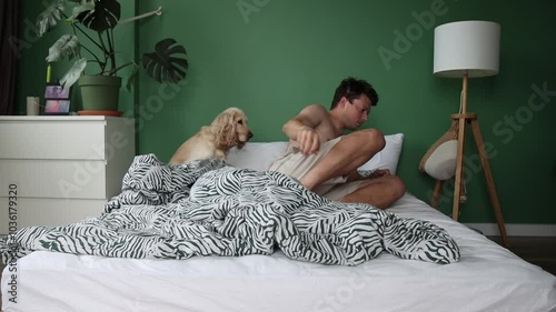 A young man gets out of bed in the morning, with his dog following closely behind. A simple, heartwarming scene that captures the bond between them in a cozy home setting.