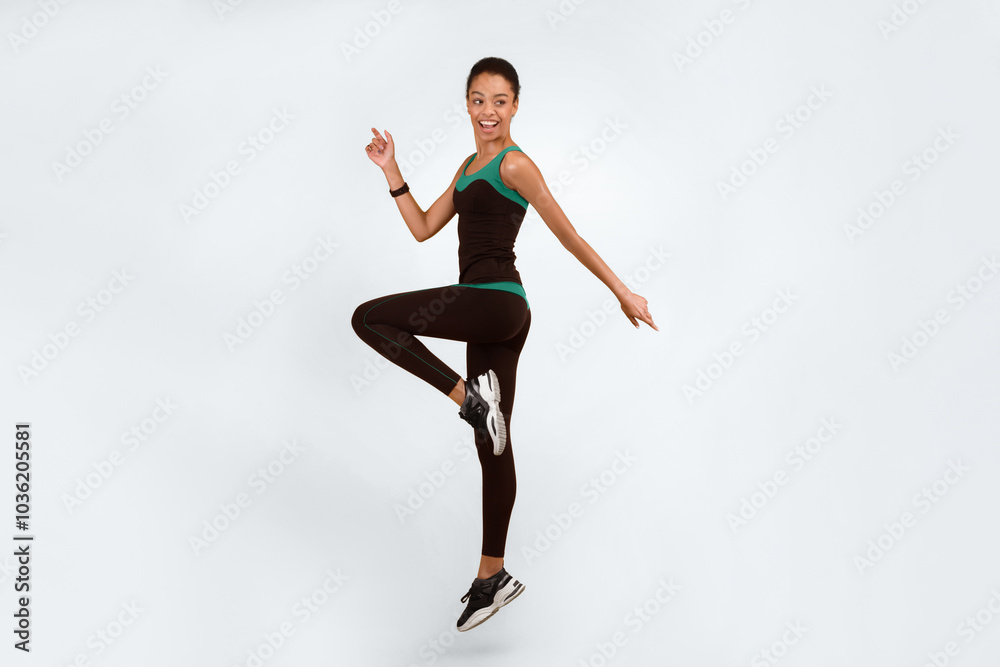 Obraz premium Fitness And Sport. Happy African American Girl Exercising Jumping Over Yellow Studio Background. Vertical, Full Length