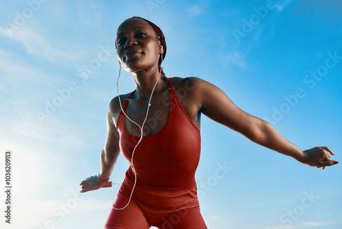 Obraz na plátně Young woman exercising outdoors in a red outfit against a blue sky