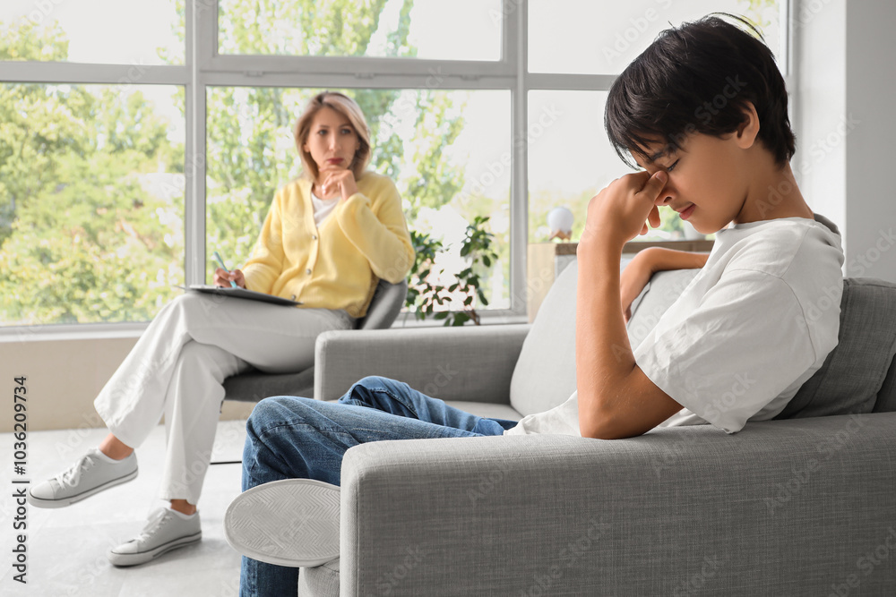Upset teenage boy sitting on sofa at psychologist's office Upset teenage boy sitting on sofa at psychologist's office