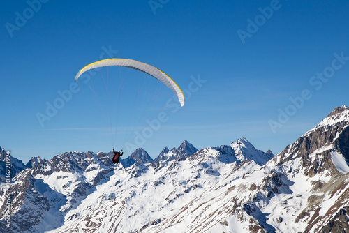 two people paragliding in tandem high in the blue sky