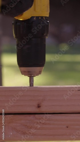 screwing into wood with screw gun outdoors vertical video.