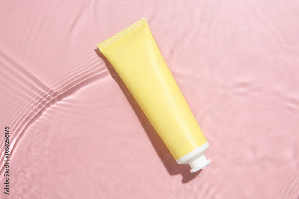 Cosmetic product. Tube with cream in water on pink background, top view Cosmetic product. Tube with cream in water on pink background, top view
