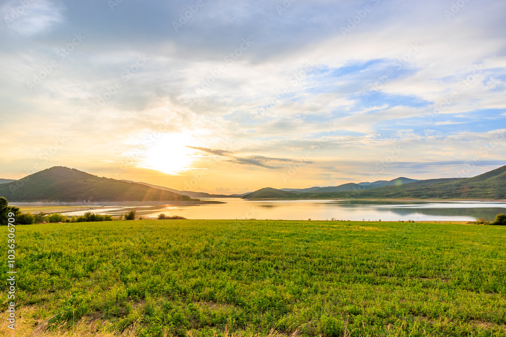 A beautiful, serene landscape with a large body of water and a field of grass A beautiful, serene landscape with a large body of water and a field of grass