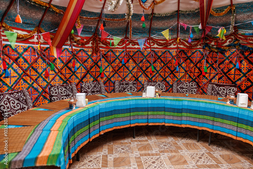 A colorful tent with a blue and green striped tablecloth, table for celebration in kyrgyz authentic yurt of nomads photo